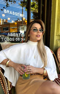 Mulher usando óculos de sol Roberta Bjoy, armação preta com dourado e lentes escuras.